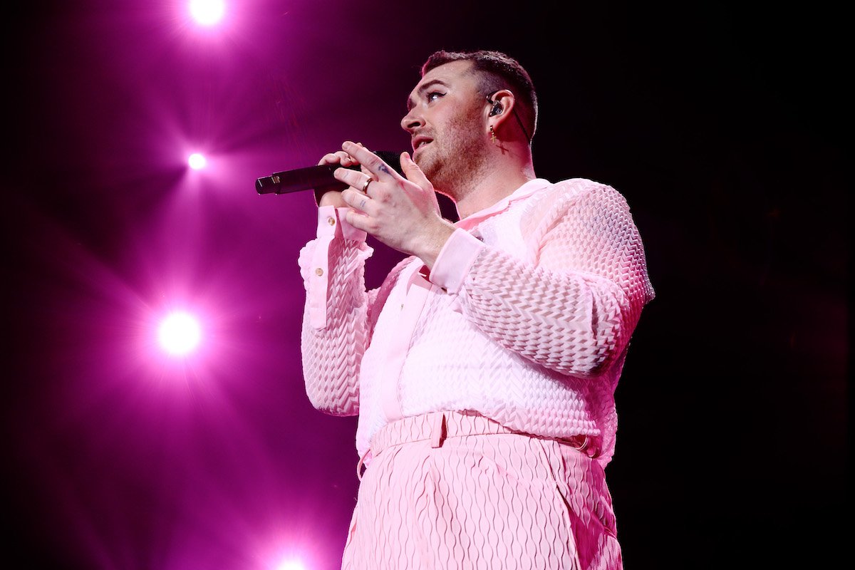 Sam Smith sings into a mic dressed in a pink ruffled top and pants