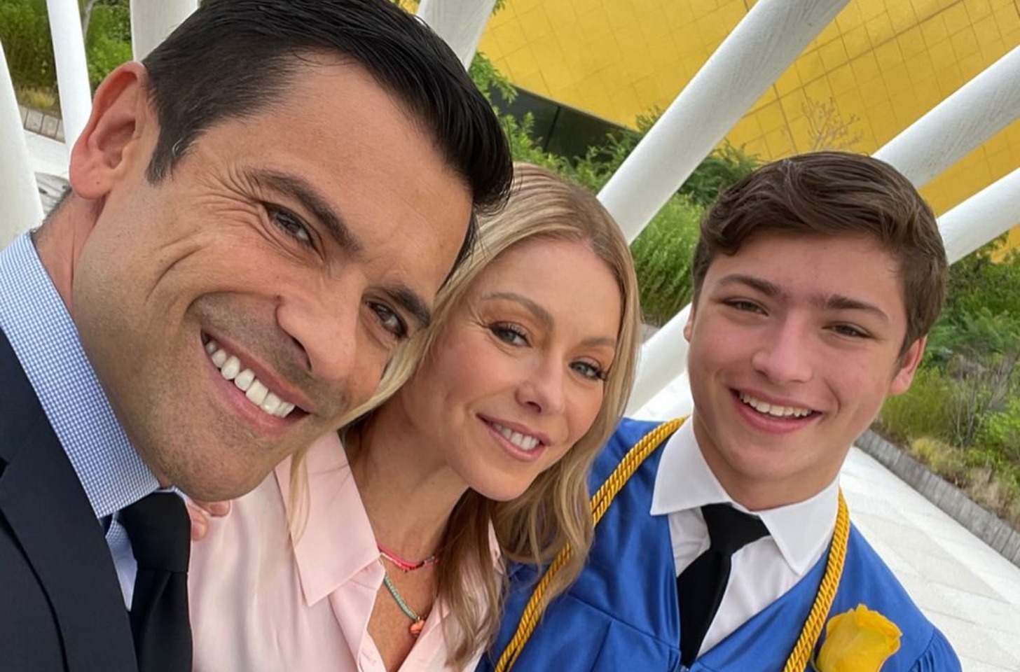 Mark Consuelos, Kelly Ripa, and Joaquin Antonio Consuelos smiling together at a graduation ceremony.