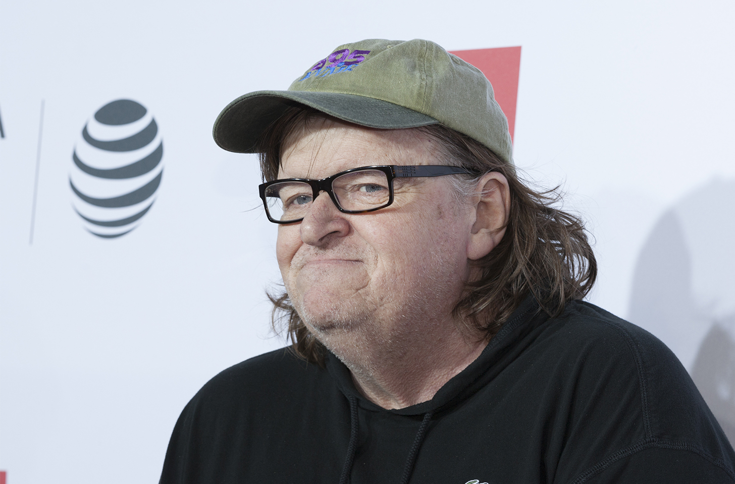 Michael Moore in a black shirt and green hat.