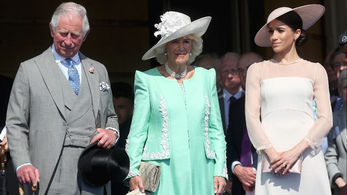 Prince Charles, Camilla Parker Bowles, and Meghan Markle listen to a speech outdoors