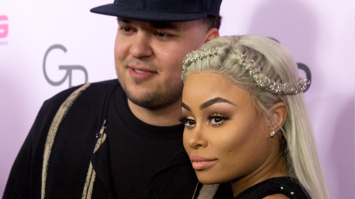 Rob Kardashian, dressed in black, poses with Blac Chyna, also in black, on the red carpet