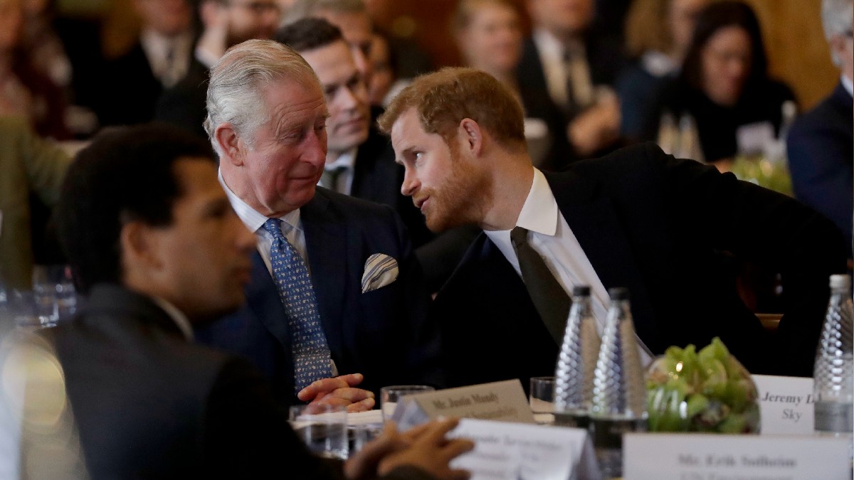 Prince Harry leans over to talk to Prince Charles during a dinner