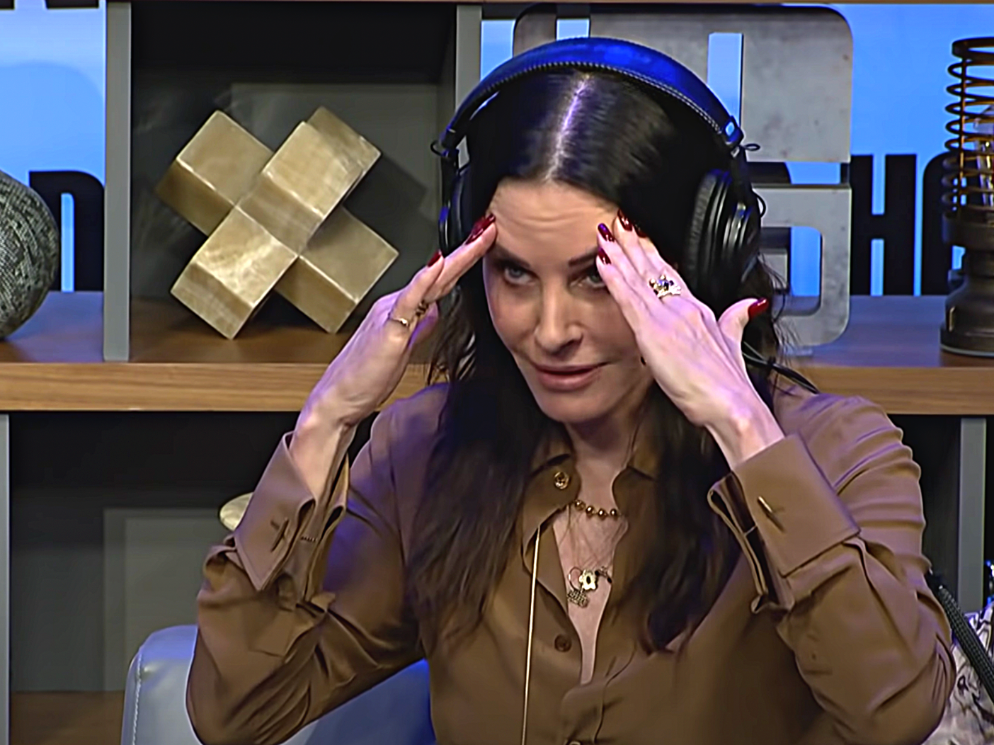 Courteney Cox with hands on forehead looking embarrassed