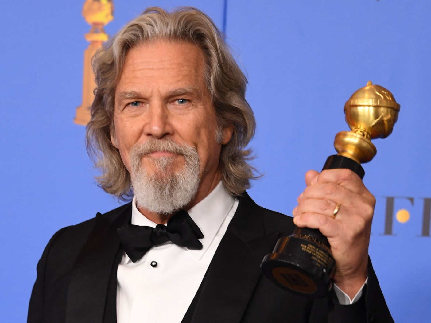 Jeff Bridges smiles while holding a Golden Globe award