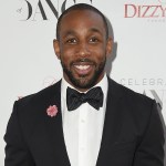 Stephen 'tWitch' Boss smiles in classic black suit and bowtie against white backdrop